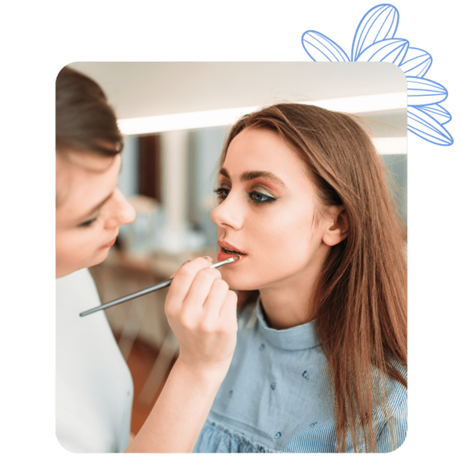 Maquilladora aplicando lápiz labial a una clienta, reflejando los servicios de belleza del centro.