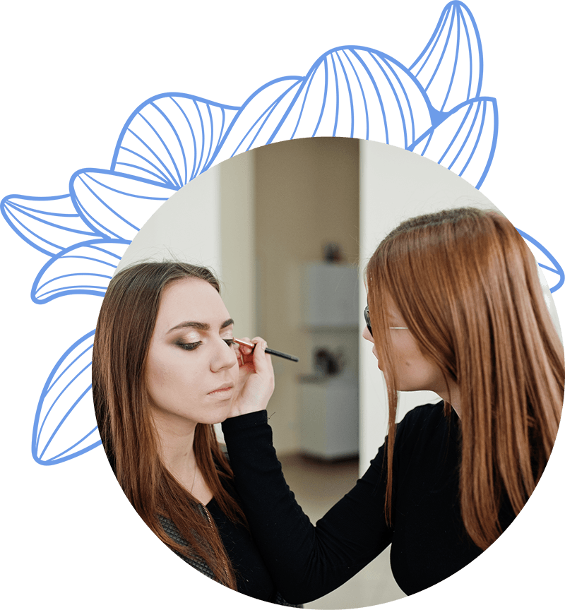 Maquilladora aplicando delineador a los ojos de una modelo, que está concentrada mientras recibe el maquillaje, en un entorno interior claro.