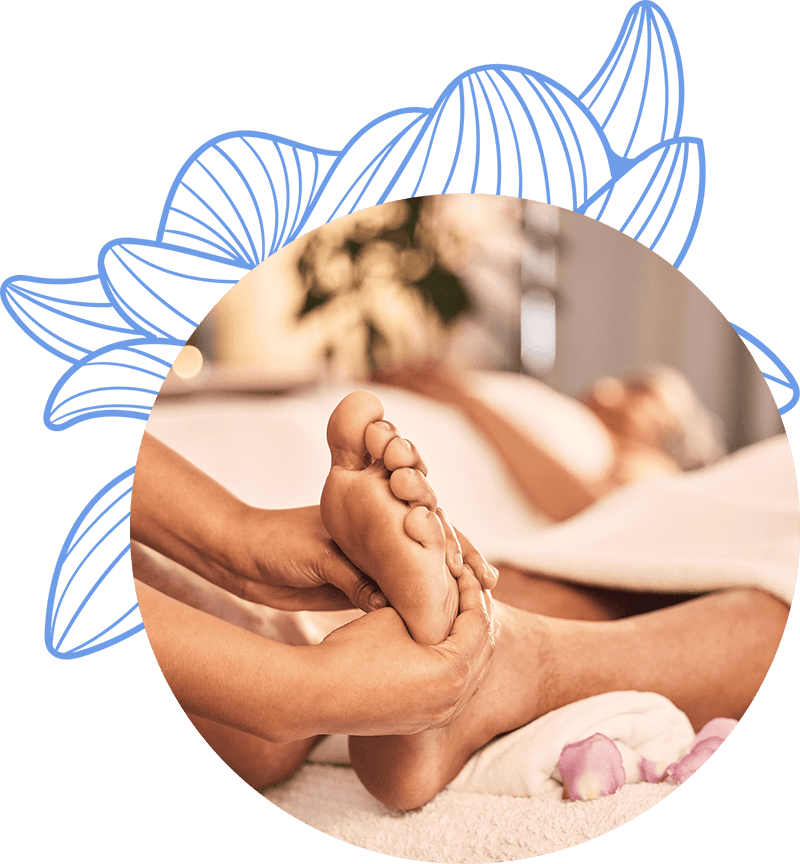 Masajista realizando un masaje de pies a una persona en un spa, mientras se ven pétalos de flores y un ambiente relajante de fondo.