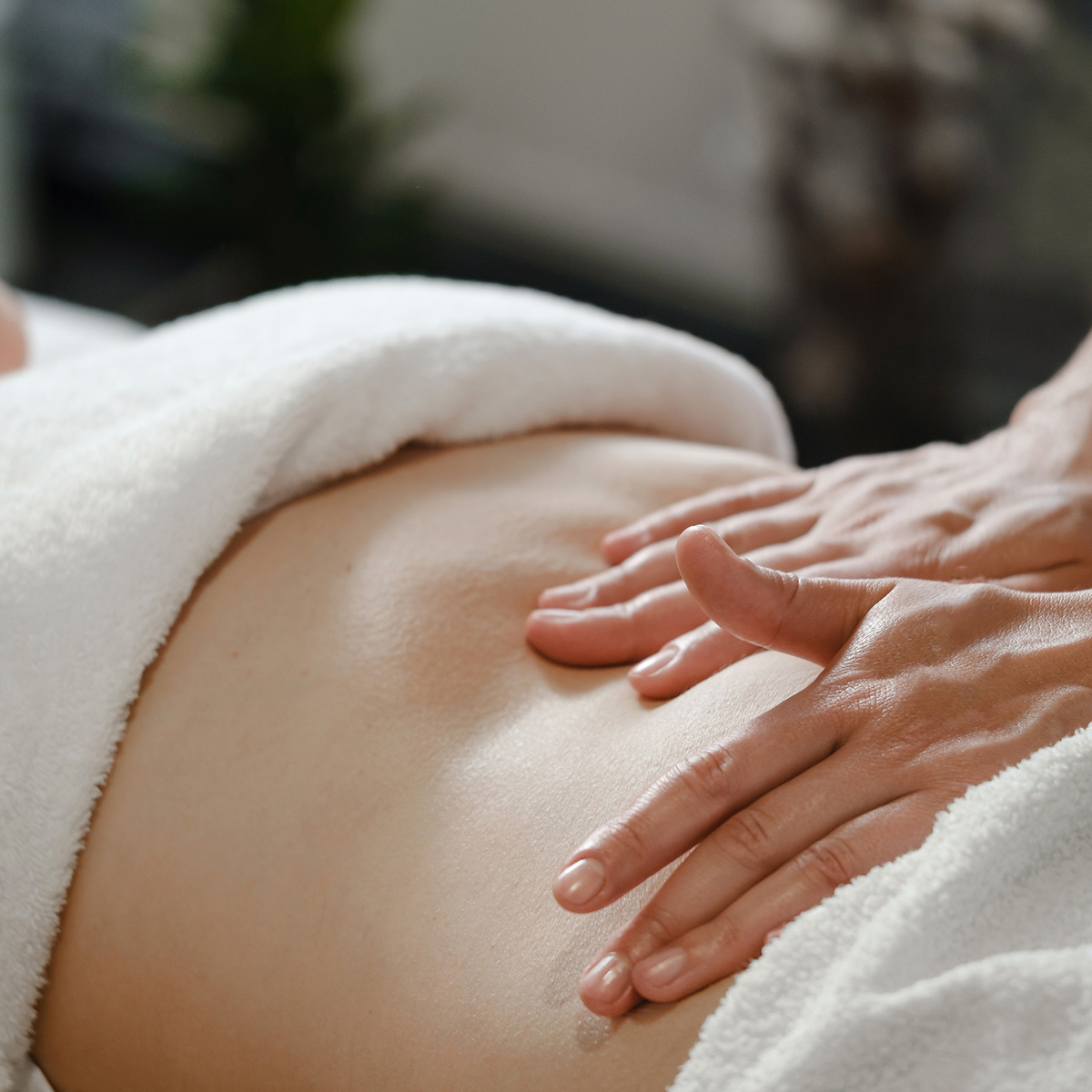 Masaje en el abdomen de una clienta, resaltando el enfoque del centro en el bienestar y la relajación.